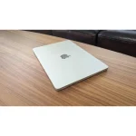 لپ تاپ اپل مک بوک ایر M5 استارلایت در حالت درب بسته روی میز کار چوبی